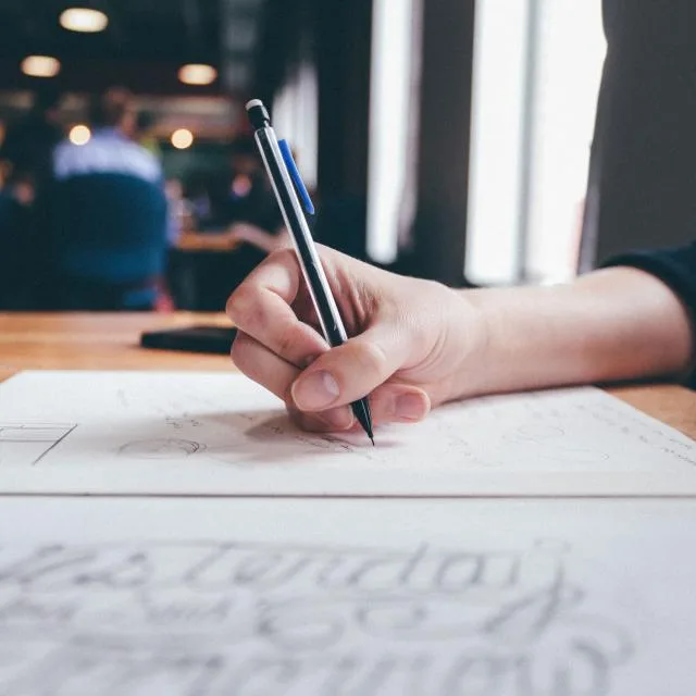 A hand drawing on paper with a pen, working out a layout by hand.