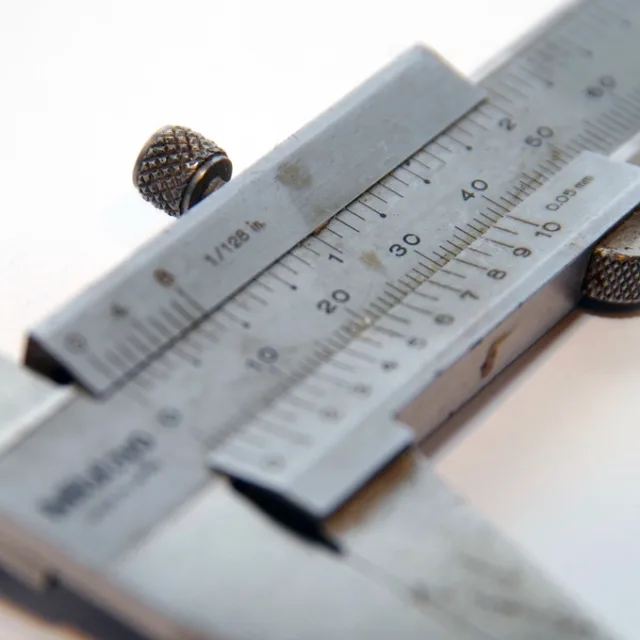 A vernier caliper closed on a workpiece, its scale reading a precise measurement.