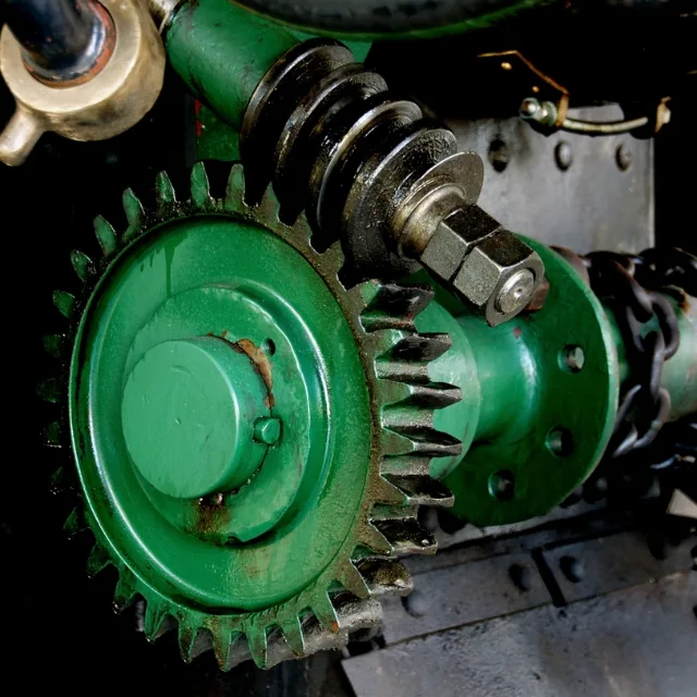 A heavy green cast-iron gear meshed with a worm drive, part of a fixed machine.