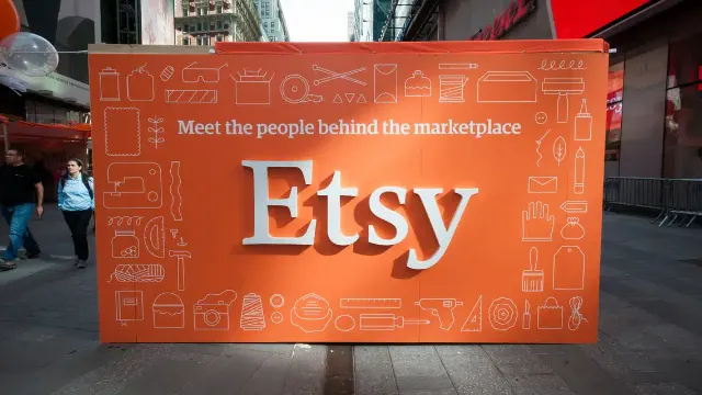 An illuminated Etsy sign above a shopfront on a street at night.