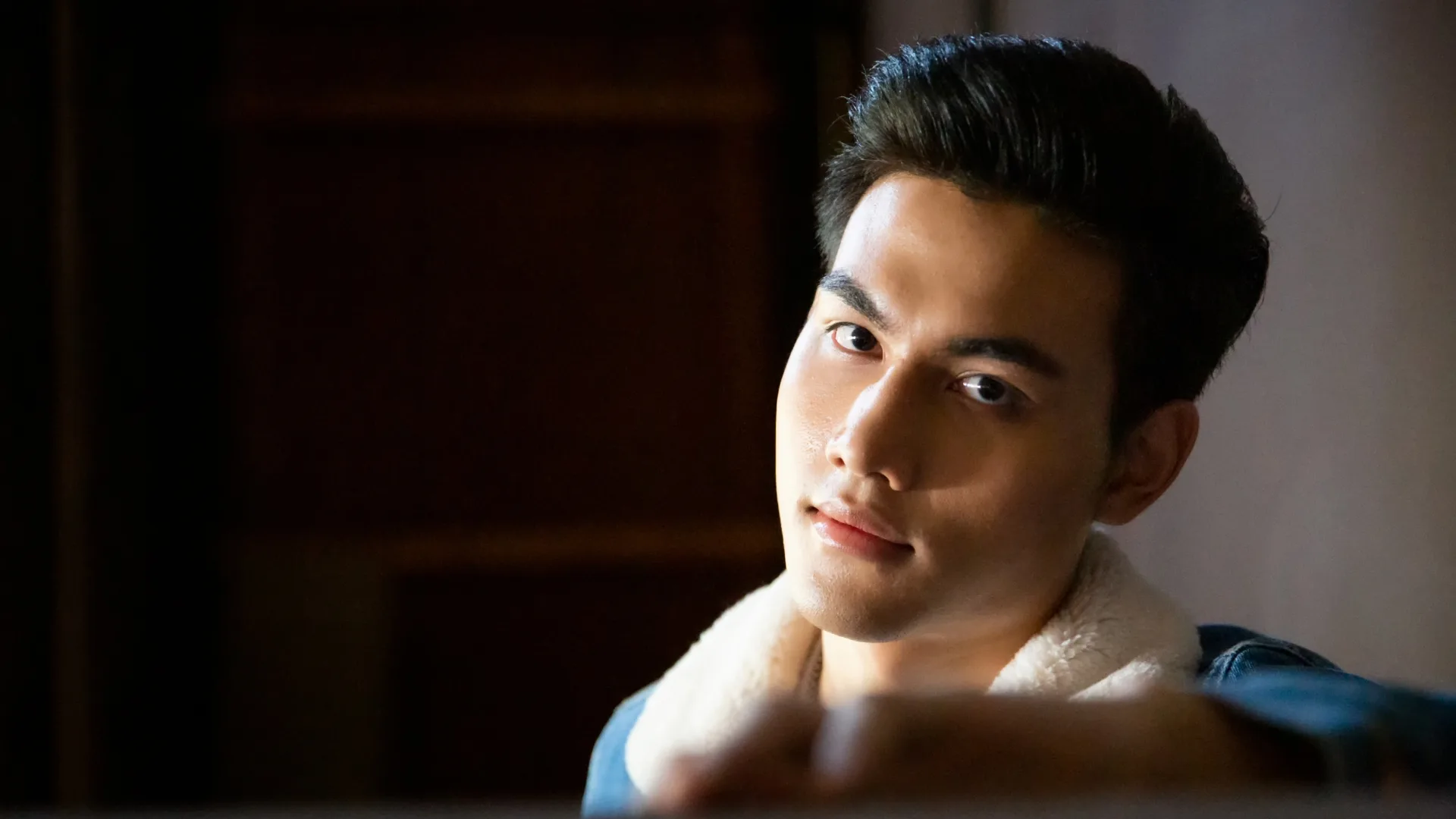 A close portrait of a man lit against a dark interior.