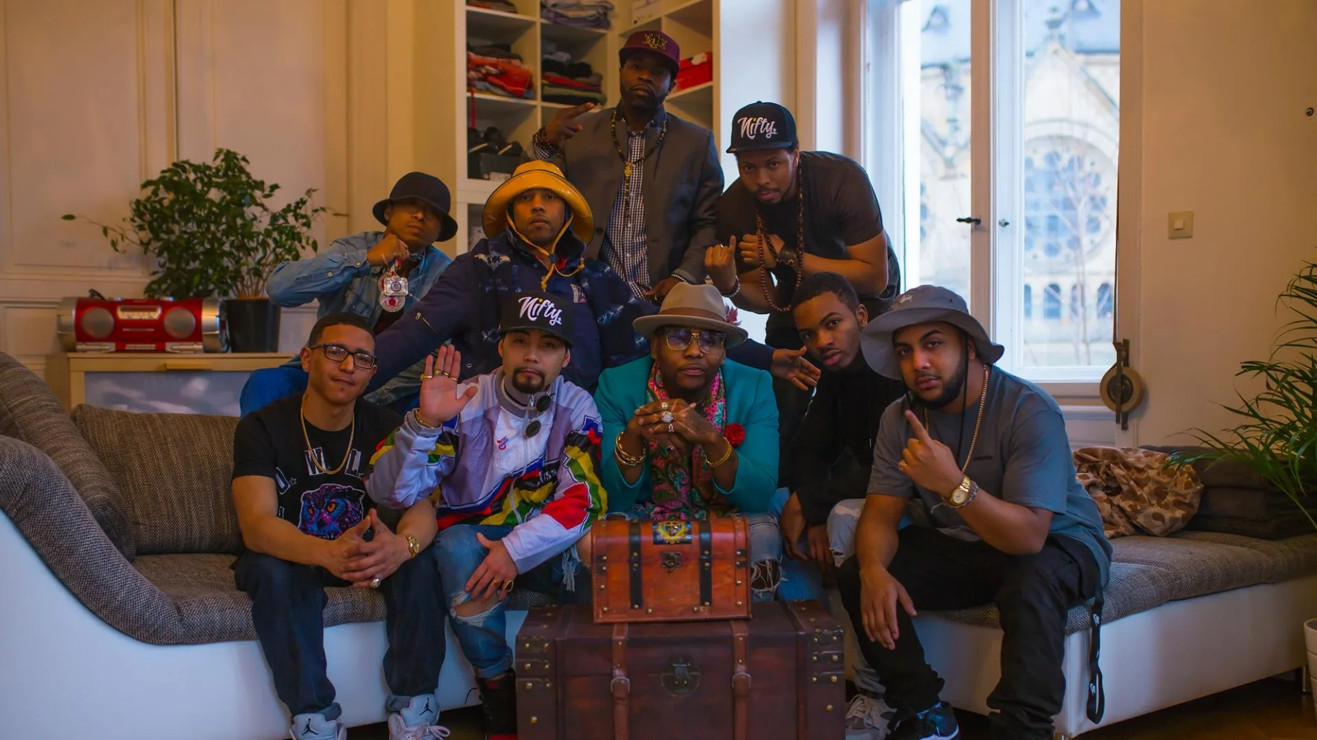 A group portrait of musicians gathered around a decorated table in a bright room.