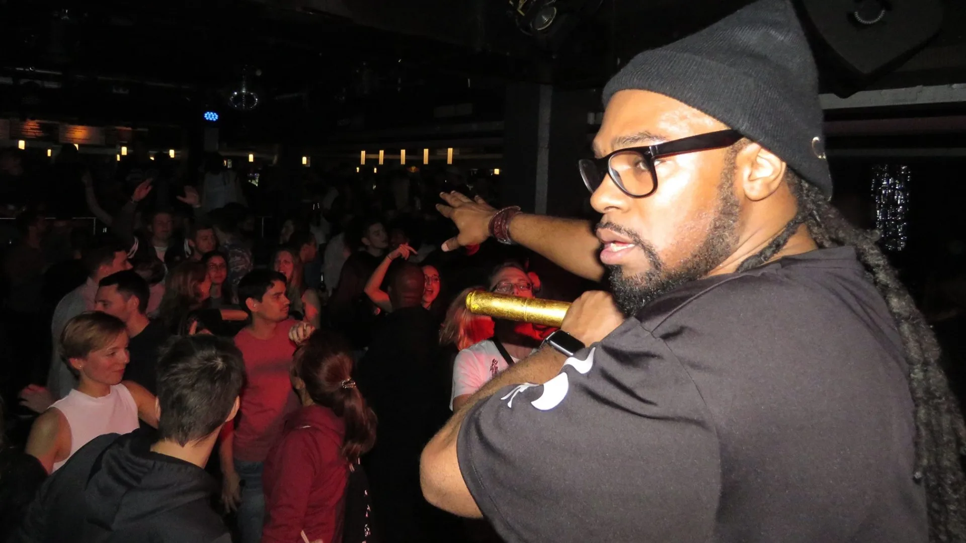 A performer holding a microphone while addressing a crowded venue.