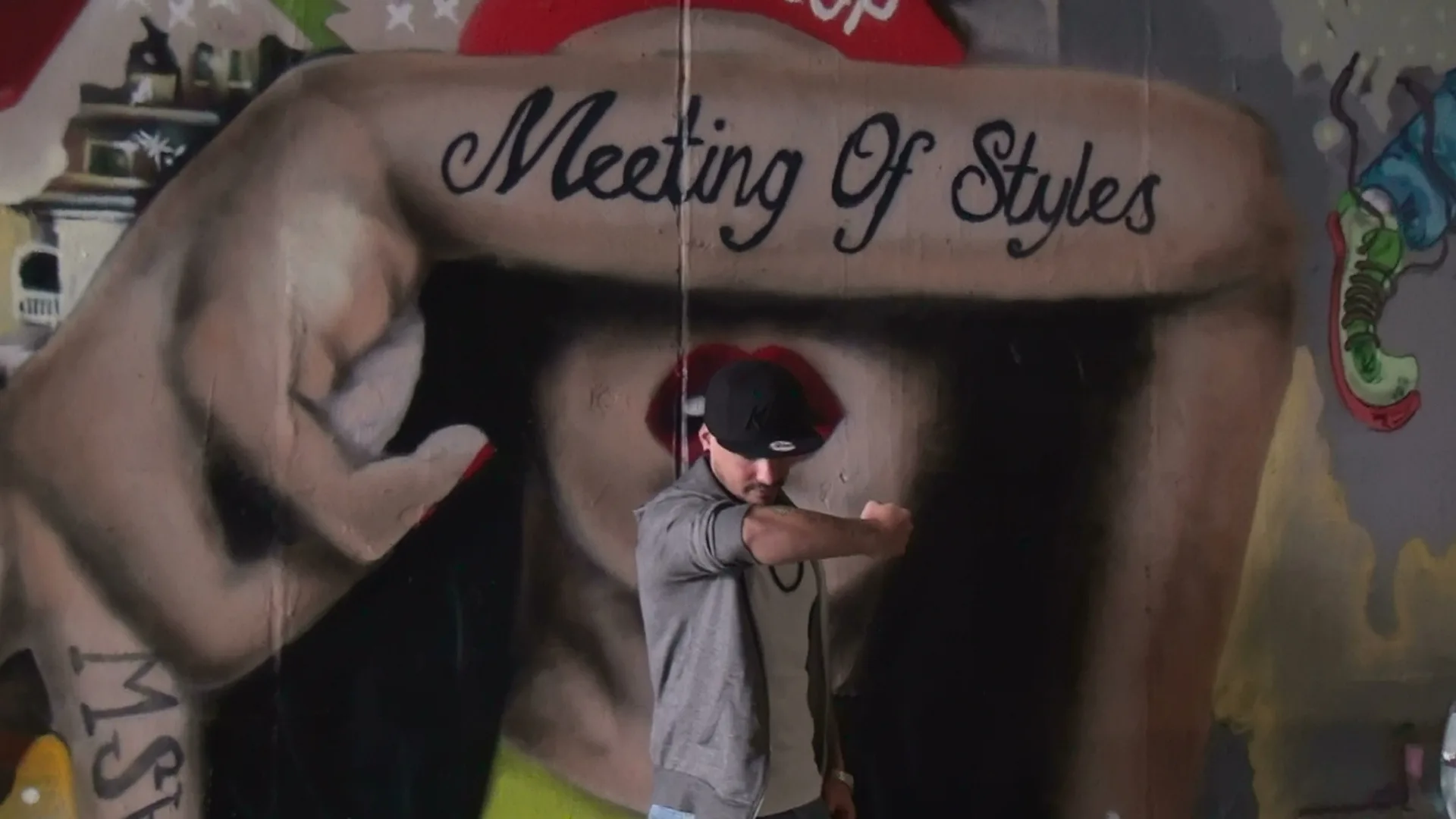 A Meeting of Styles mural featuring a painted hand and artist at work.